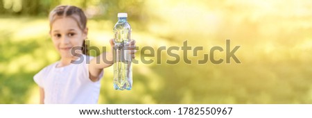 Little girl holding water bottle. Outdoor training. Thirsty. Plastic drink. Summer time. Pretty teenager lifestyle. Sunny day. Kid hand. Happy people. Horizontal banner
