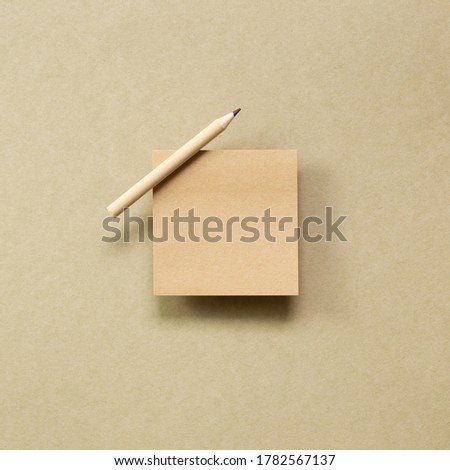 Memo note pad with wooden pencil on brown kraft paper background. top view, copy space
