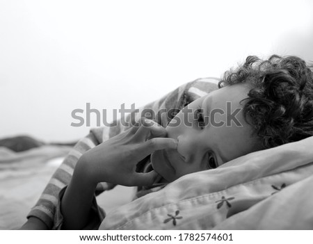 boy picking his nose in bed with white background stock photo