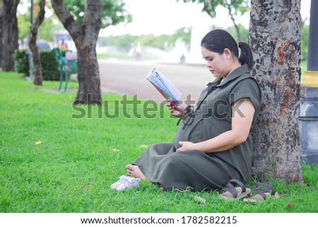 Pregnant Asian women read books or stories for their babies in the womb for the development of a newborn baby. In the park