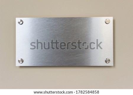 Template mockup of metallic brushed chrome entrance signboard on pastel wall