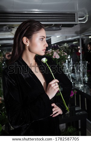 Fashion photosession in flower shop refrigerator. Model wearing designer black velvet suit and looking aside. Perfect skin and natural make up. Image for your advertisment or magazine editorial
