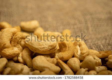 A pile of cashew nuts on burlap with a rough texture surface texture. Close up.