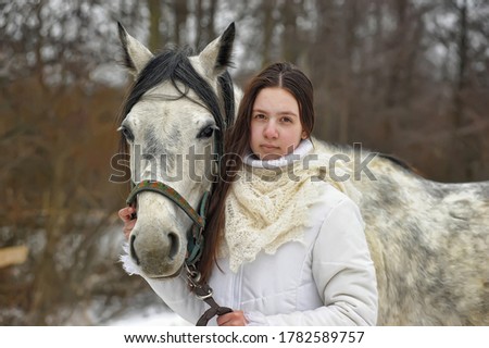 girl in a white coat in winter with a horse portrait