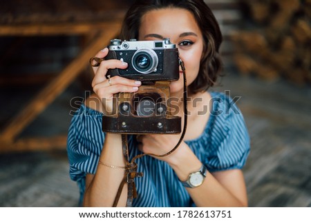 close-up of beautiful brunette girl in blue dress with retro camera in hands.