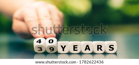 Hand turns dice and changes the expression "39 years" to "40 years". Royalty-Free Stock Photo #1782622436