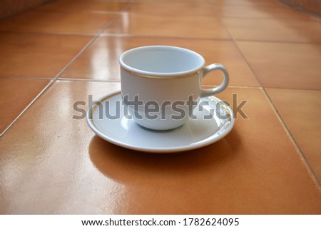 a picture of cup and saucer on the floor 