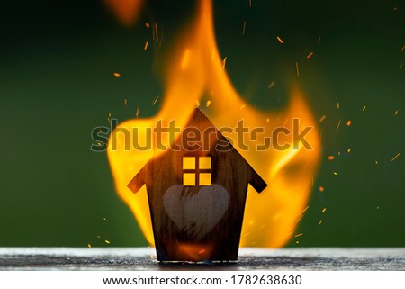 Toy house in the flame of fire. The concept of fire safety. Insurance protection