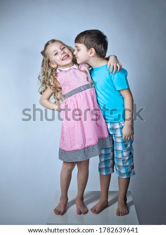 Cute couple of little boy and blonde girl having fun and trying kiss