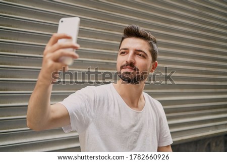 Young handsome man making video call on smartphone isolated on grey background. Male model taking a selfie.