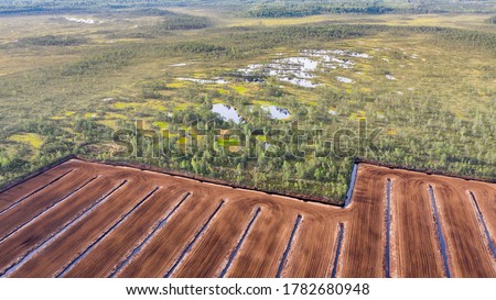 Aerial view to the bog landscape with the remaining natural elements and destroyed area by peat extraction. This  activity have severe impact to water protection, biodiversity and climate change  Royalty-Free Stock Photo #1782680948