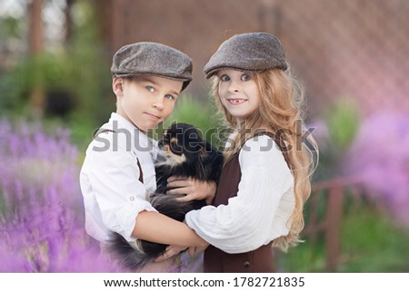 Children, a boy and a girl with a small Chihuahua dog in their arms. Hug. In a blooming garden.
