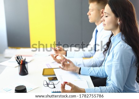 Employees in office sit at table and meditate. Workers overwork and energy recovery concept