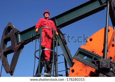Oil and Gas Industry. Pump jack maintenance and repair. Worker in action at pump jack oil well. 