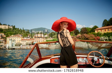 Stunning female model photographed on a wooden speed boat touring Lake Como Italy 