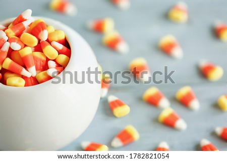 Halloween holiday candy corn in a white bowl over a blue wooden background for Trick or Treat.