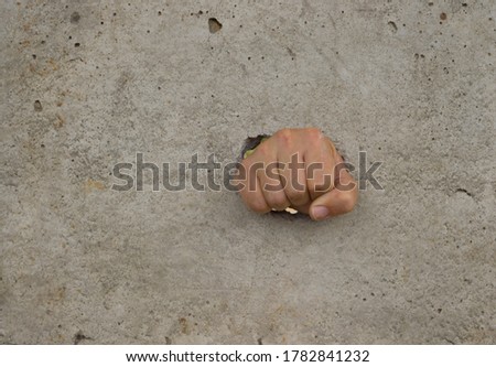 A fist breaks through a concrete wall. Fist through the concrete. Overcoming obstacles concept.