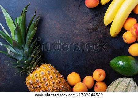 Concept of healthy vegan food. Pineapple, banana, apricot, melon, avocado on the black background. Top view image