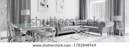 Panorama of white and gray living room in glamour style with glass dining and coffee tables and quilted corner sofa Royalty-Free Stock Photo #1782848969