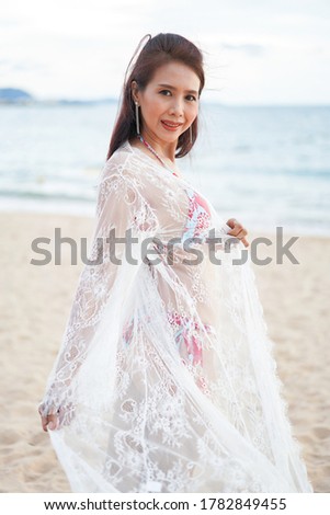 portrait of​ smiling woman​ in​ bikini standing​ on seashore. Holiday summer. leisure activities. 
