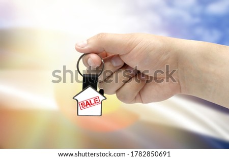 A man's hand holds a keychain in the form of a house with the inscription Sale on the background of the flag of State of Colorado. Property and real estate sale concept.