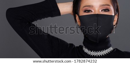Close up on Eye make up Portrait of 20s Asian Woman black hair black turtle neck dress. Fashion Girl poses view looks, make up cosmetic on Eyes, wear protective face mask over gray Background isolated