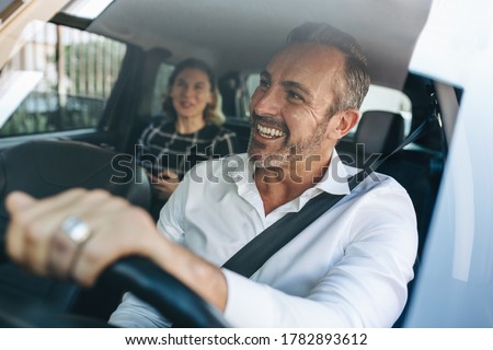 Taxi driver talking to a female passenger sitting in backseat. Businesswoman using taxi ride to go to work. Royalty-Free Stock Photo #1782893612
