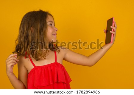 Portrait of a pretty happy little girl taking a selfie isolated over bright background