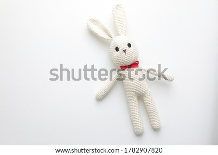 Handmade children's toy - soft crocheted white Bunny. Large knitted stuffed rabbit with eyes made of buttons on white background - the concept of happy childhood Royalty-Free Stock Photo #1782907820