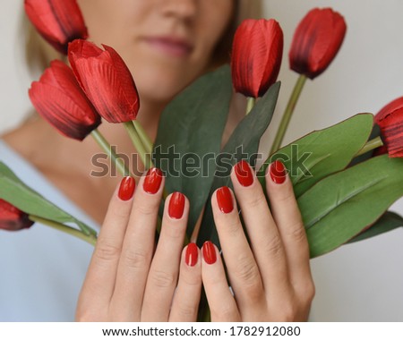 A manicure procedure in the beauty saloon, red nail polish with tulips flowers