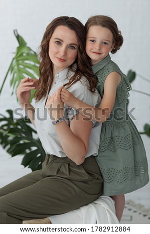 mom hugs her daughter in a room with green plants freshness morning tenderness having a good time together