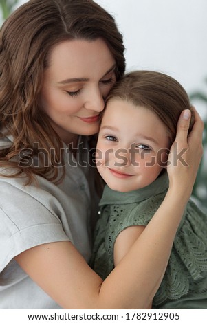 mom hugs her daughter in a room with green plants freshness morning tenderness having a good time together