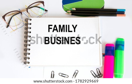 In a white notebook is a FAMILY BUSINES inscription, next to pencils, glasses, graphs and diagrams.