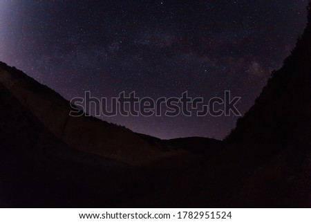 Night sky with Milky way galaxy and canyon, mountains with trees