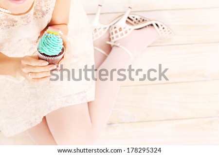 A picture of a woman holding a delicious cupcake over wooden background