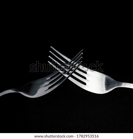 two forks crossed on a dark background.