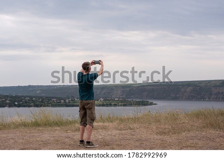 Man tourist taking photo on beautiful view of landscape with mobile smart phone camera, mobile photography with smart phone.