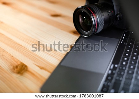 Workplace of photographer on a wooden table background with copy space for text design. Modern laptop and digital camera lens. Minimalism top view
