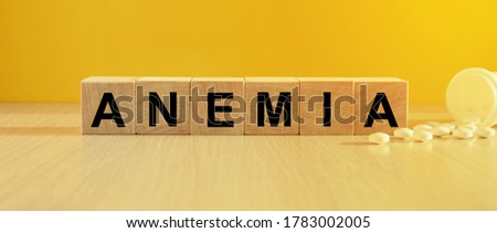 The inscription anemia on wooden cubes, bright yellow background. Health and medicine concept.