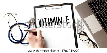 Doctor's hand with pan and paper plate, stethoscope and keyboard on the white background. VITAMIN E.