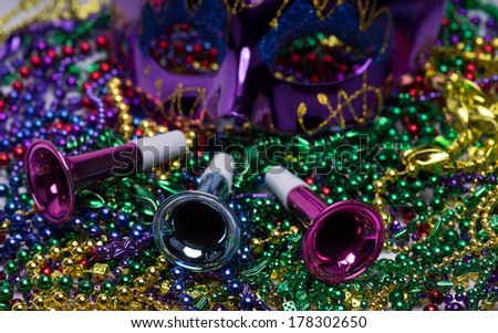 Mardi Gras celebration.  Purple Mardi Gras mask and horns on top of colorful beaded background