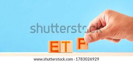 etf concept. man folds wooden blocks into etf lettering
