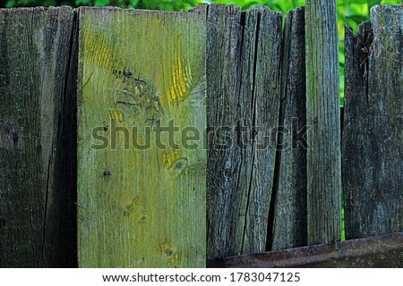 An old fence in the countryside with broken pickets. Selective focus. Abandoned countryside. Concept with old broken fence at pasture. Nature background in vintage style