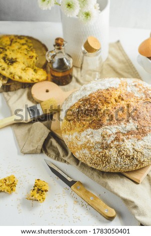 Homemade sourdough bread and flatbread, some eggs, oil, sesame, white background.