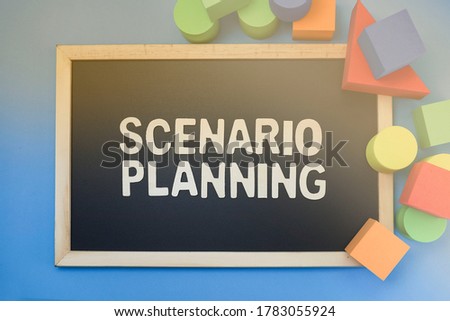 Block letters on scenario planning on black chalkboard and colorful blocks on blue background