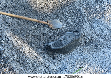 metal spade and plastic bucket on pebbles for construction