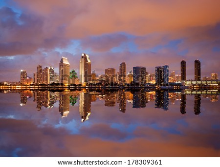 Skyline cityscape of San Diego downtown skyscrapers at night with lights reflecting into the ocean