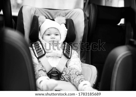 Adorable baby girl with blue eyes sitting in car seat. Toddler child in winter clothes going on family vacations and jorney. Safe travel, children safety, transportation concept