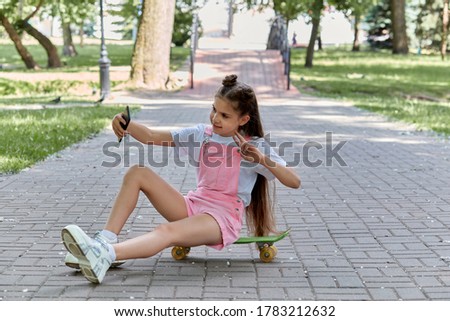 The girl takes a selfie and goes snowboarding in the park. Summer holidays.