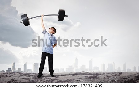 Cute boy of school age lifting barbell above head Royalty-Free Stock Photo #178321409